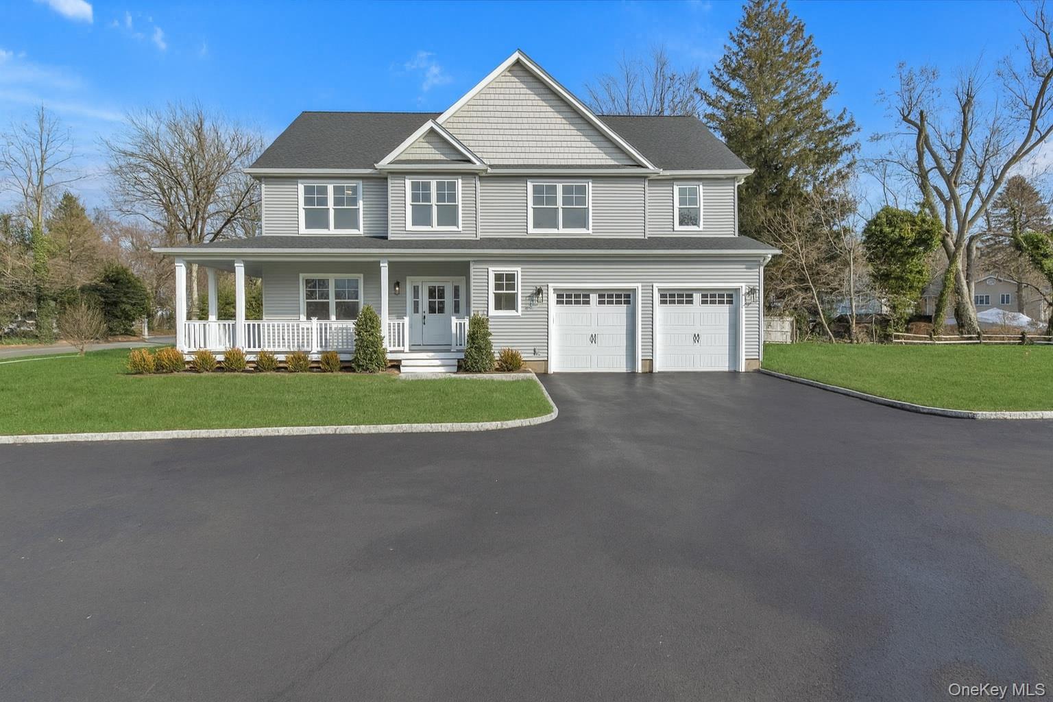 View of front of house with a front yard, covered porch, asphalt driveway, and an attached garage