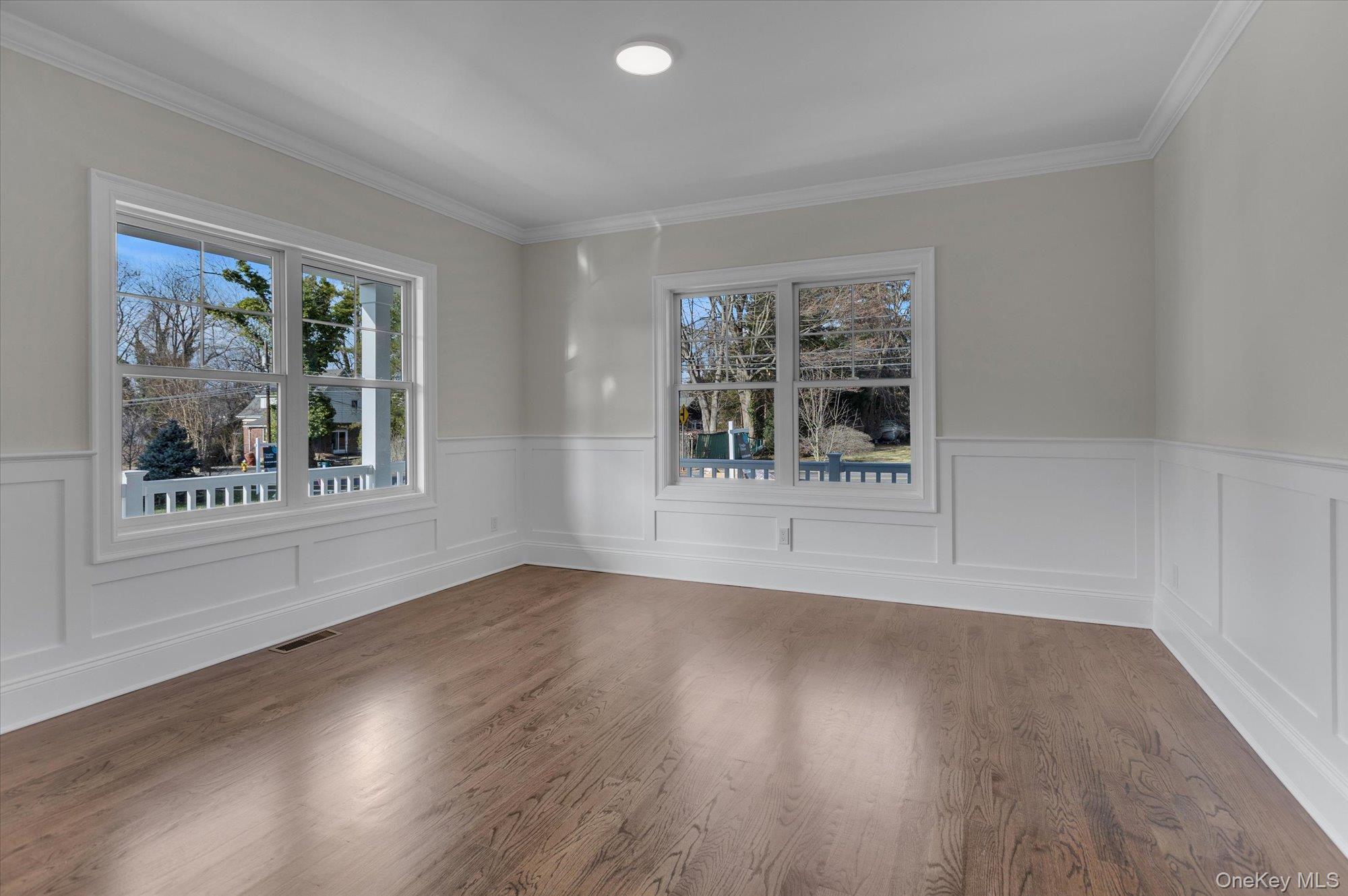 44 North Woodhull Road Huntington, NY 11743 - Photo 13 of 26 Spare room with wood finished floors, healthy amount of natural light, a wainscoted wall, and ornamental molding