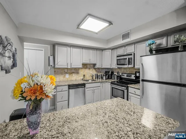 a kitchen with stainless steel appliances granite countertop a refrigerator sink stove microwave and cabinets