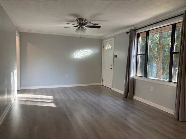 a view of an empty room with a window and wooden floor