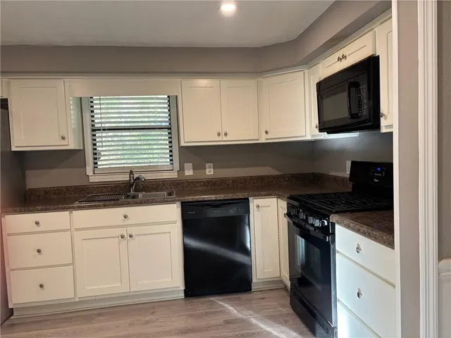 a kitchen with granite countertop white cabinets and black appliances