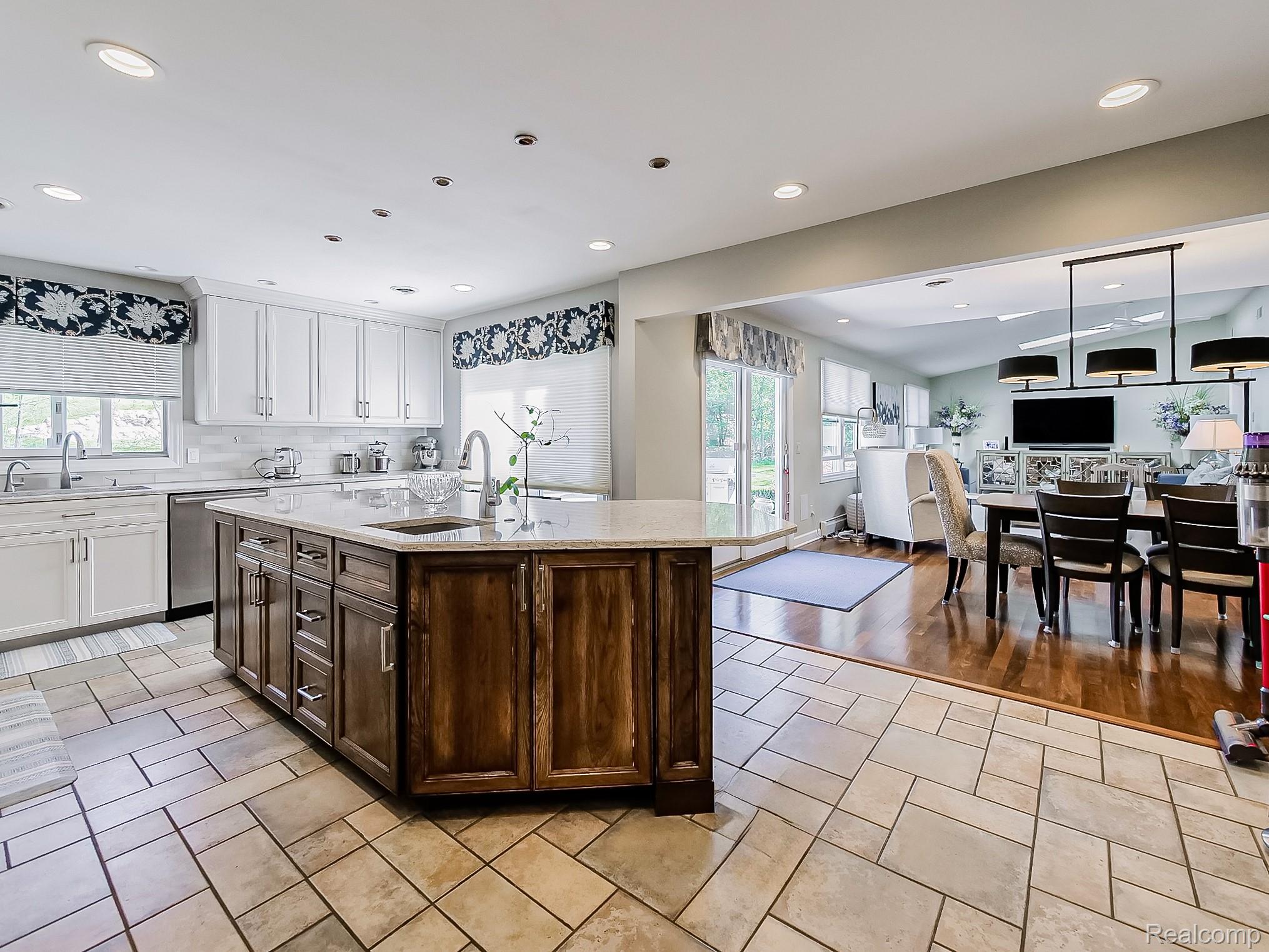 3720 East Clarkston Road Oakland, MI 48363 - Photo 56 of 60 Dual tone kitchen with two tone color scheme, a center island with sink, light stone counters, tasteful backsplash, and open floor plan