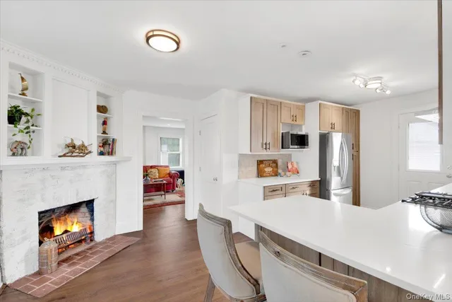 a living room with stainless steel appliances furniture a fireplace and a open kitchen view