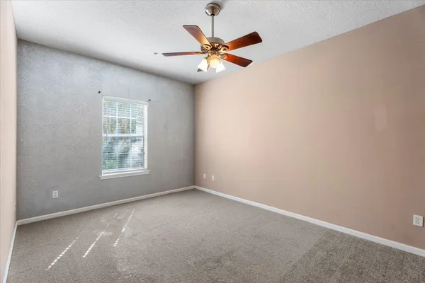an empty room with a ceiling fan and window