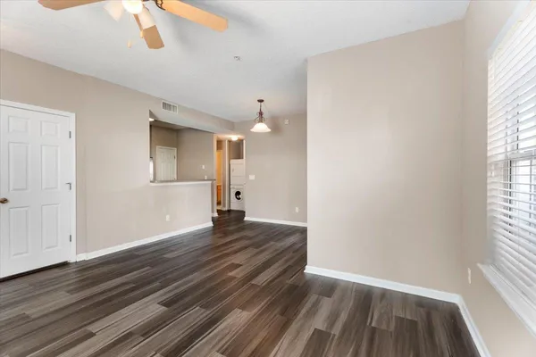 a view of an empty room with wooden floor and a window