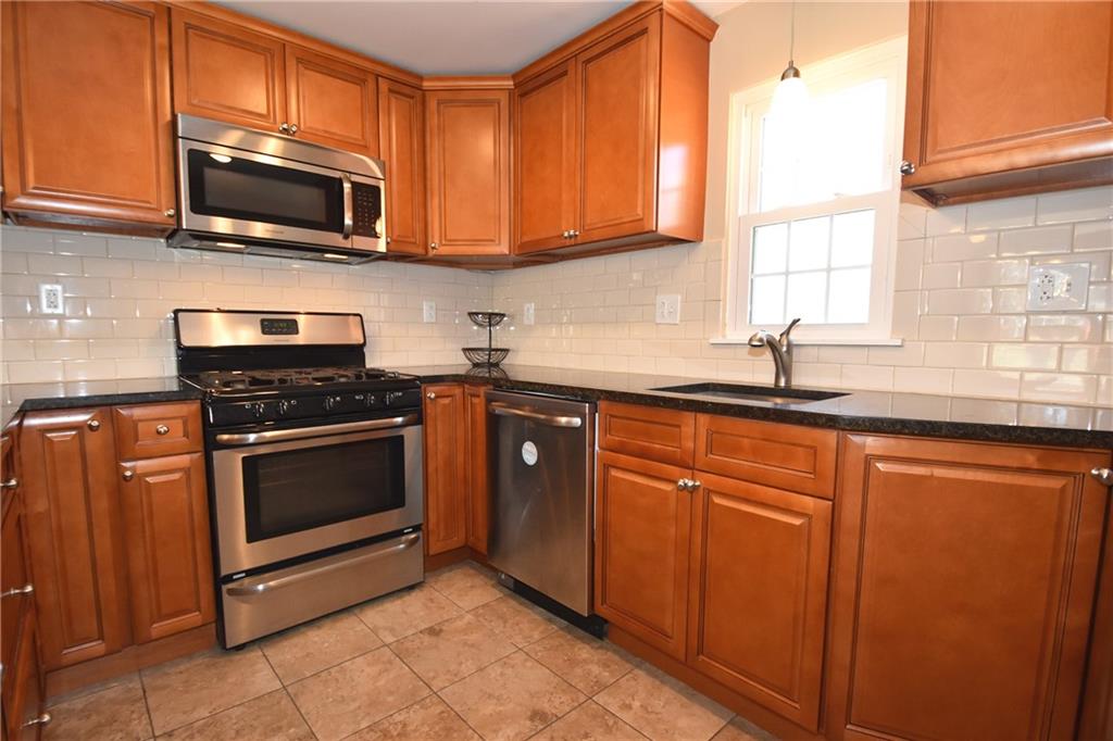 5470 Library Road Bethel Park, PA 15102 - Photo 9 of 24 a kitchen with granite countertop a sink a stove a microwave and cabinets