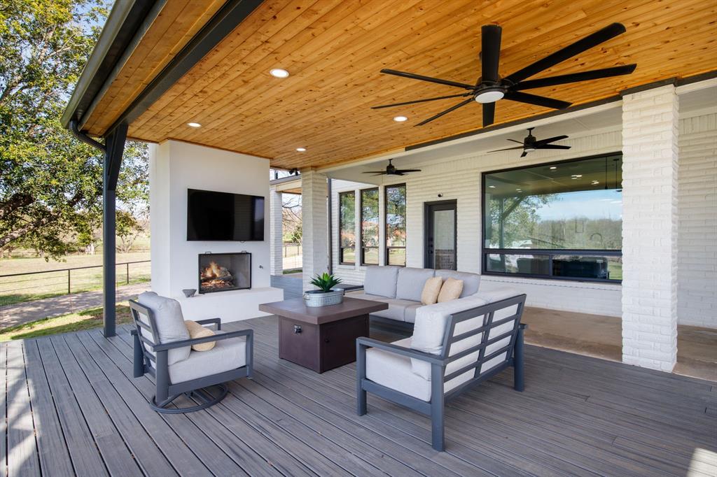 245 Barnes Bridge Road Sunnyvale, TX 75182 - Photo 32 of 40 Enjoy year-round outdoor living on the covered deck, anchored by a cozy fireplace and a sweeping backdrop of your own approximate 6-acre pastoral retreat.