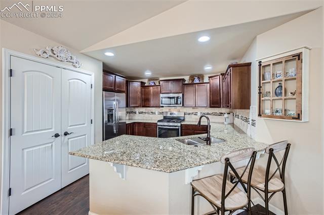 11399 Rill Point Colorado Springs, CO 80921 - Photo 8 of 28 Kitchen with decorative backsplash, kitchen breakfast bar and stainless steel appliances