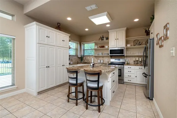 a kitchen with stainless steel appliances kitchen island granite countertop a refrigerator and a stove top oven