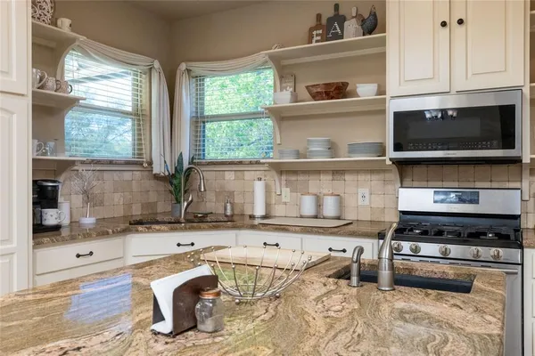 a kitchen with stainless steel appliances granite countertop a stove a sink and a microwave