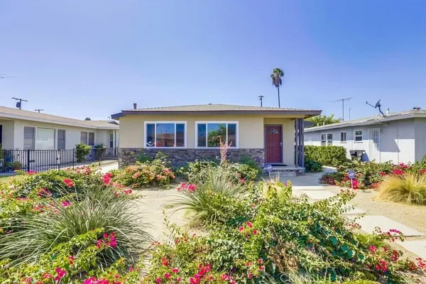 a front view of a house with a big yard and potted plants