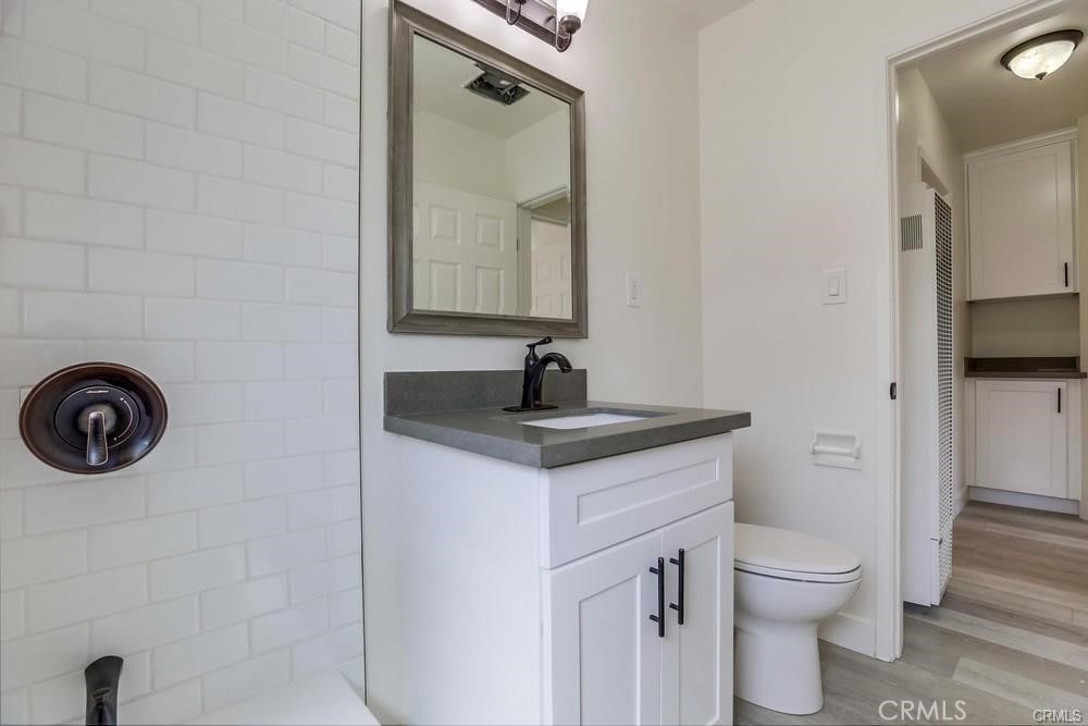 8716 Buckles Street Downey, CA 90241 - Photo 12 of 22 a bathroom with a granite countertop toilet a sink and a mirror
