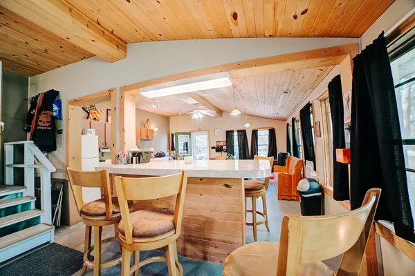 a dining hall with stainless steel appliances kitchen island granite countertop a table chairs and a refrigerator