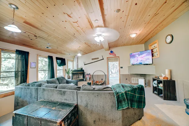 a large living room with stainless steel appliances furniture a fireplace and a large window