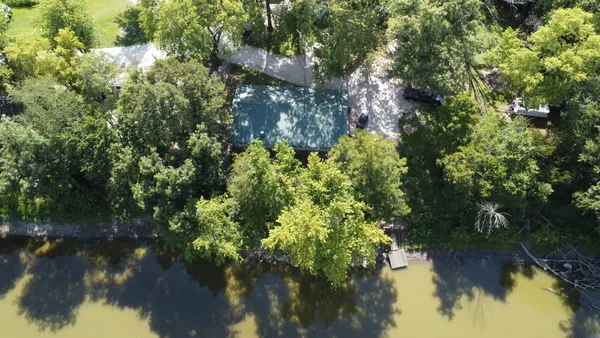 a view of a patio with a dining table and chairs under an umbrella with large trees