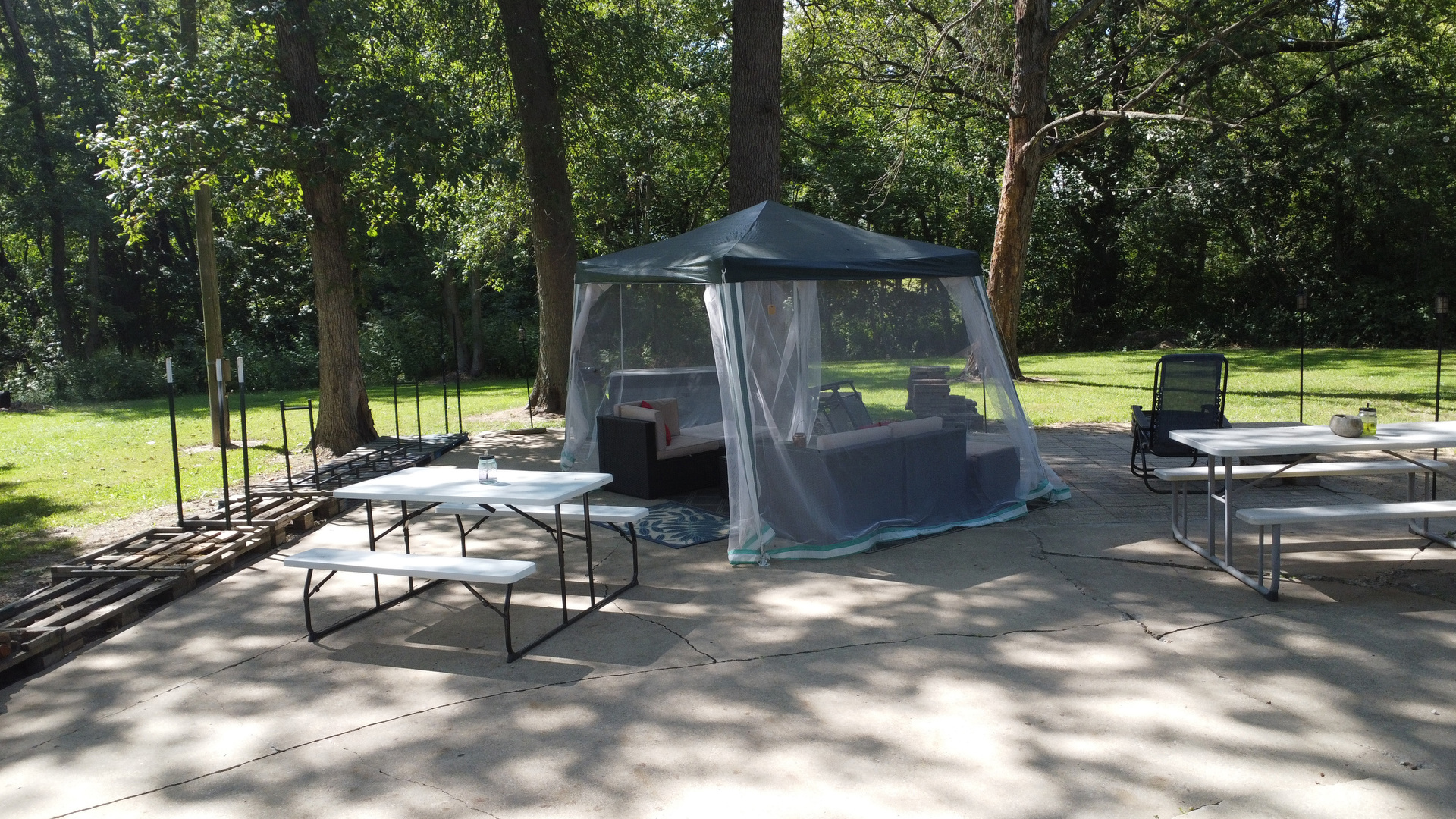 1500 East 2400th Road North, Unit 66 Ashkum, IL 60911 - Photo 31 of 37 a view of a patio with a dining table and chairs under an umbrella with large trees