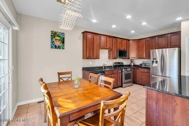 a kitchen with granite countertop a refrigerator a stove a sink a dining table and chairs with wooden floor