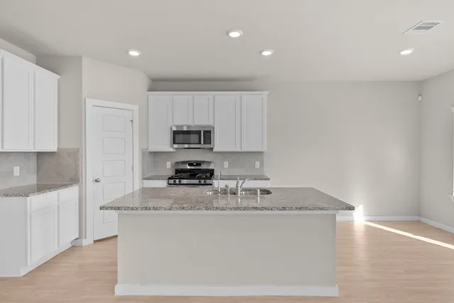 a kitchen with stainless steel appliances granite countertop a sink stove and microwave