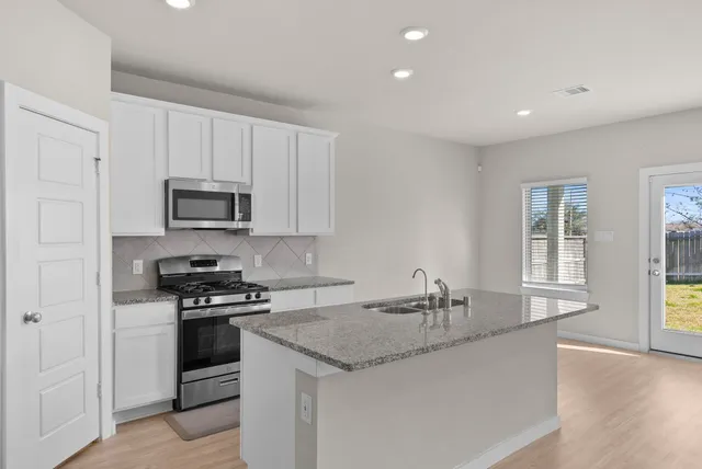 a kitchen with stainless steel appliances granite countertop a sink stove and microwave
