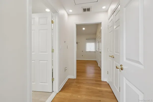 a view of a hallway with wooden floor and a bathroom
