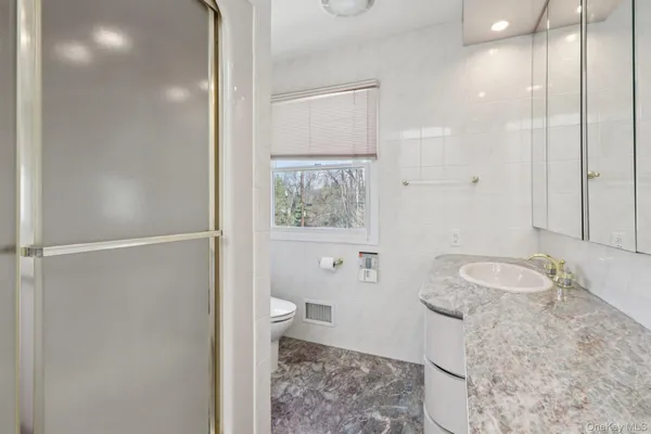 a bathroom with a granite countertop sink toilet and shower