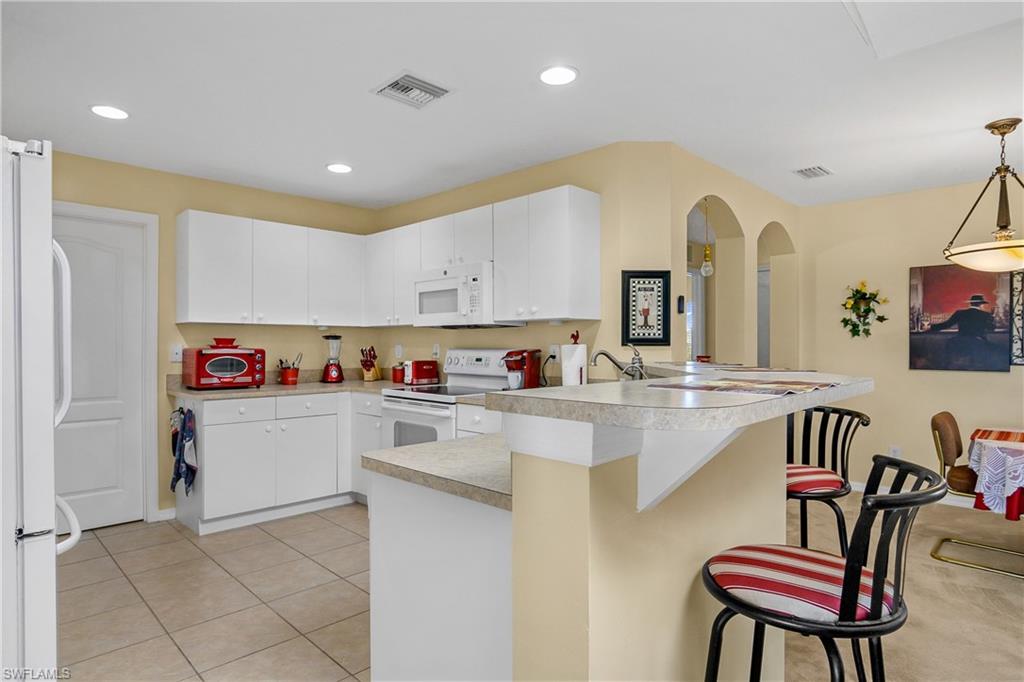 113 Northeast 29th Street Cape Coral, FL 33909 - Photo 7 of 19 a kitchen with kitchen island a stove a table and chairs in it