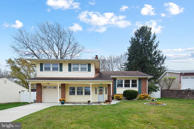 a front view of a house with a garden and trees