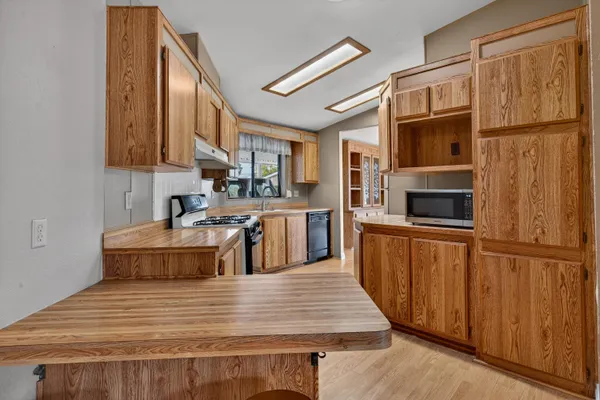 a kitchen with stainless steel appliances granite countertop a stove a sink and a microwave