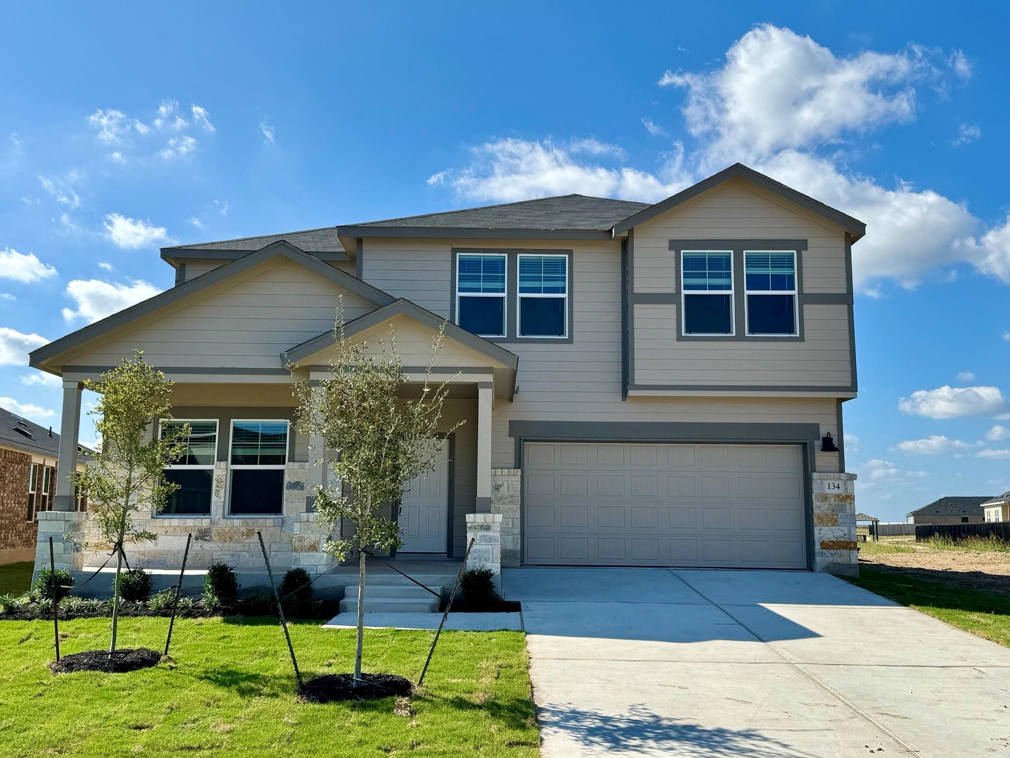 Craftsman inspired home with a garage, driveway, a front lawn, and stone siding