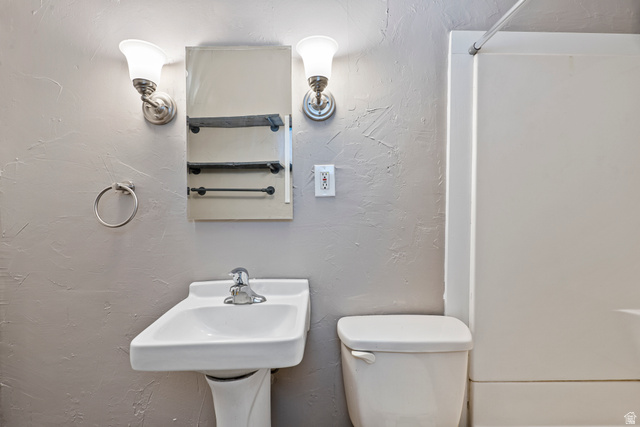 75 600 West Provo, UT 84601 - Photo 18 of 26 Pedestal sink with chrome faucet, flanked by a wall-mounted medicine cabinet with integrated shelving and dual sconce lighting