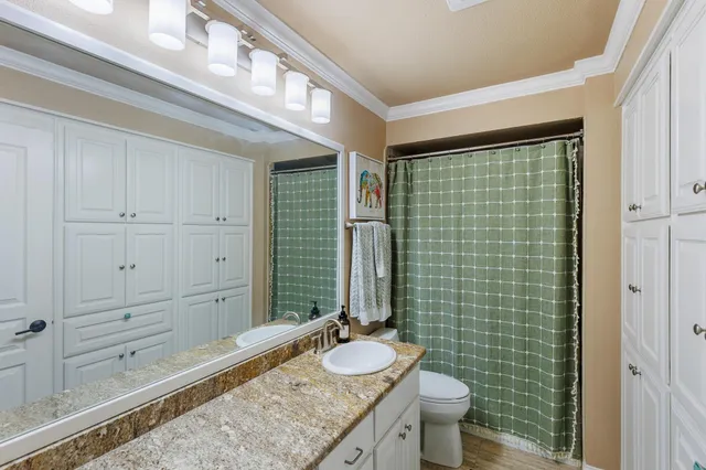 a bathroom with a granite countertop sink a toilet a mirror and shower