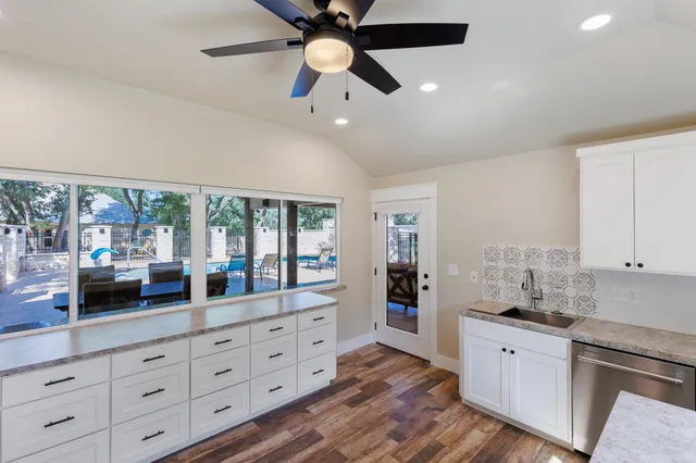 a large kitchen with granite countertop a large window and white stainless steel appliances