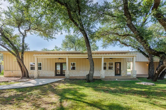 a view of a house with a yard and a large tree