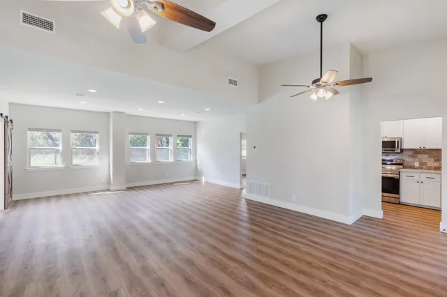 a view of an empty room with window and wooden floor