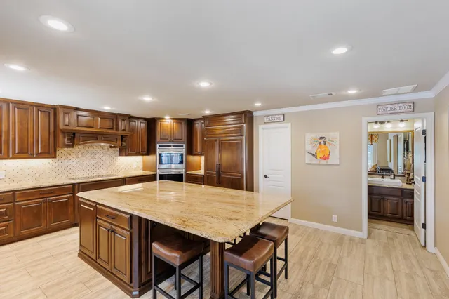 a kitchen with stainless steel appliances granite countertop a kitchen island a stove and a sink