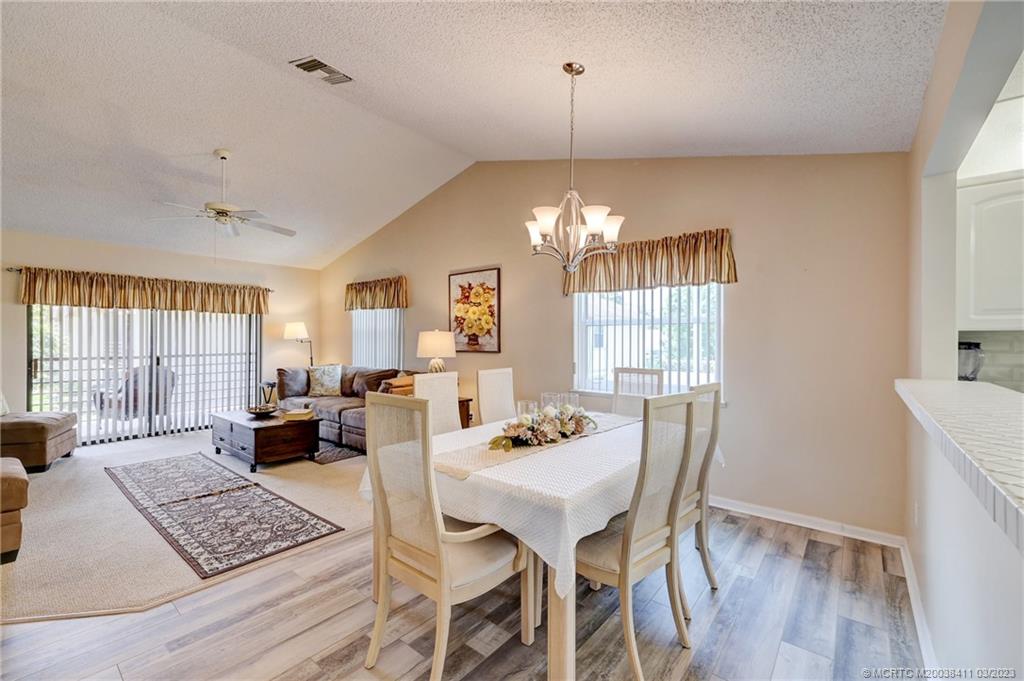 1881 Southwest Palm City Road, Unit H102 Stuart, FL 34994 - Photo 3 of 30 a view of a dining room with furniture a chandelier and wooden floor