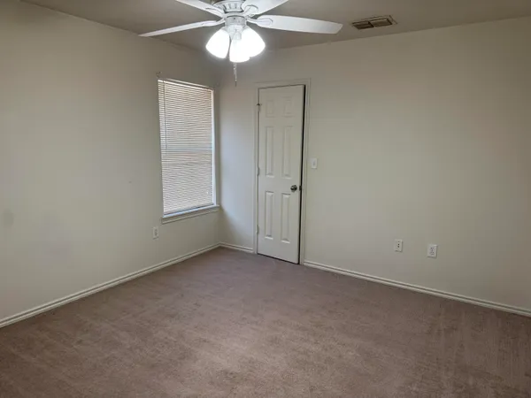 an empty room with a chandelier fan and windows