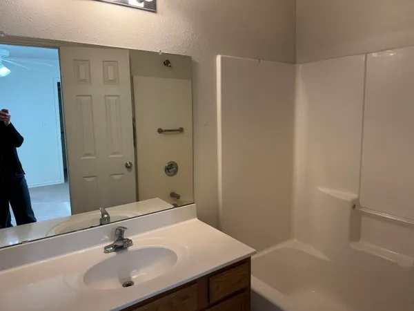 a bathroom with a sink shower and a mirror