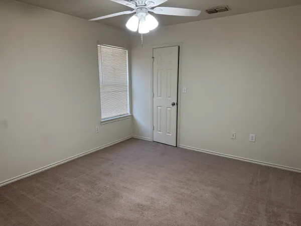an empty room with a chandelier fan and windows