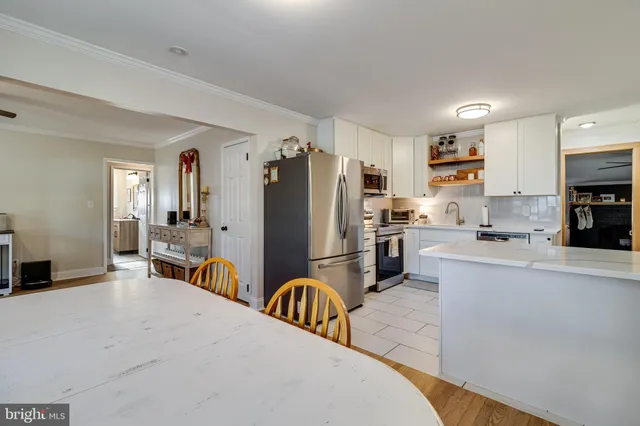 a kitchen with stainless steel appliances a refrigerator a stove a sink dishwasher and white cabinets with wooden floor