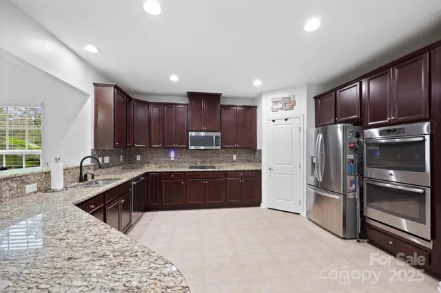 a large kitchen with granite countertop a large counter top stainless steel appliances and cabinets