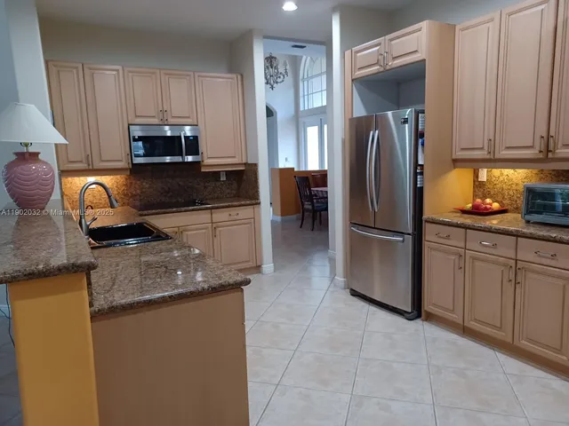 a kitchen with granite countertop a refrigerator a stove a sink a counter space and cabinets