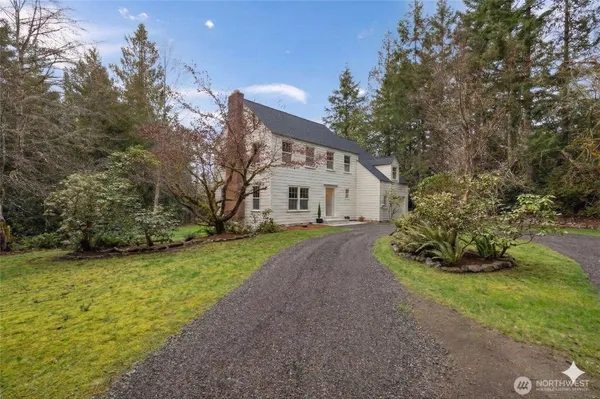 a white house with a large tree with yard