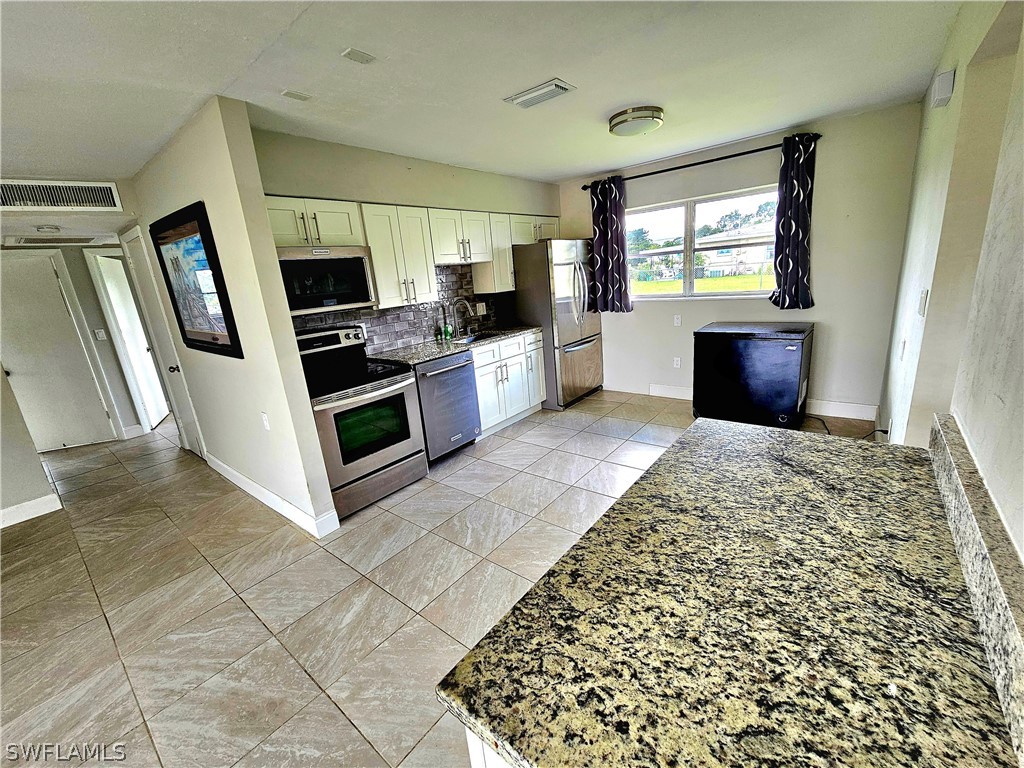 200 Oregon Road West Lehigh Acres, FL 33936 - Photo 3 of 18 a large kitchen with a stove a refrigerator and a sink