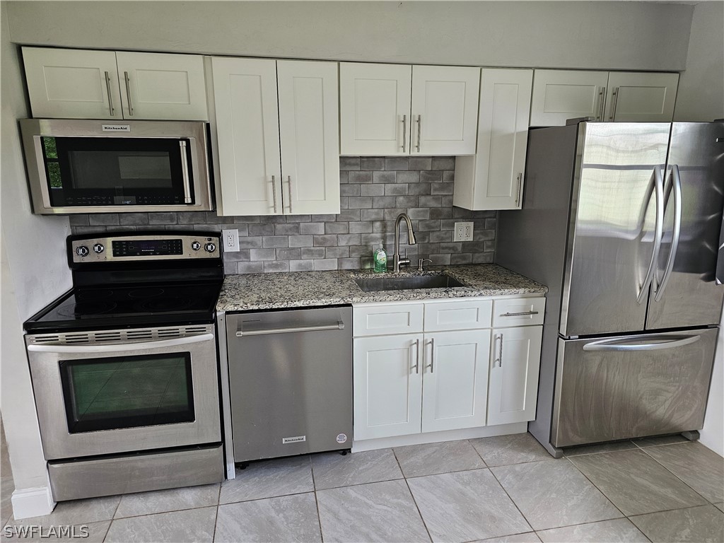 200 Oregon Road West Lehigh Acres, FL 33936 - Photo 4 of 18 a kitchen with cabinets stainless steel appliances and a sink