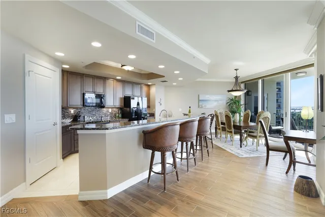 a kitchen with stainless steel appliances granite countertop a table chairs refrigerator sink and cabinets