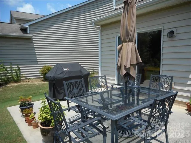 a view of a patio with table and chairs potted plants and floor to ceiling window