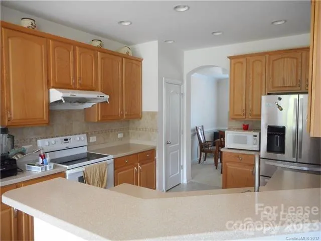 a kitchen with stainless steel appliances granite countertop a refrigerator a stove and a sink with wooden cabinets