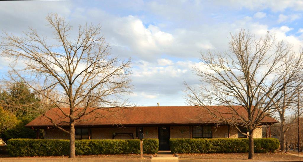 a view of a white house with a large tree