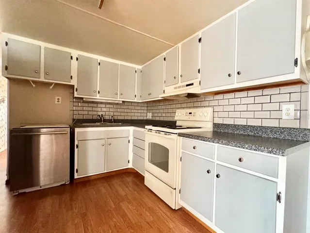 a kitchen with granite countertop white cabinets and white appliances